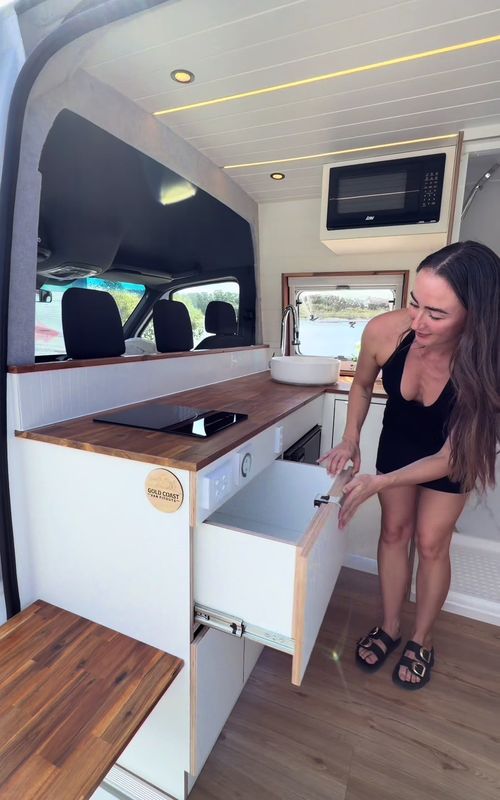 Check out this MWB Sprinter transformation! Fit with:  ✔️ Double bed ✔️ Ducted aircon ✔️ Massive dog bed (yes with aircon too🐶) ✔️ L-shape kitchen with Bushman fridge, induction cooktop, sink + overhead flatbed microwave ✔️ Internal shower (with hot/cold water) ✔️ TWO massive fixed under-mount water tanks ✔️ 4 windows with blackout shades + fly screens ✔️ Waterproof VJ panel board walls & ceiling Power system that doesn’t mess around: ⚡ 600Ah i04 lithium battery ⚡ 3000W Enerdrive inverter ⚡ Full system control from your phone Comfort upgrades: ❄️ Truma Safire fixed aircon with custom vents through the bed frame 🌬 MaxxFan + 2 Sirocco fans 💡 6 ceiling downlights + 2 LED rails 🌈 Multi-colour kitchen LED lighting And of course: ✔️ Campervan Modification Plate ✔️ Electrical certification ✔️ Plumbing certification This isn’t just a van. It’s a fully self sufficient, luxury home on wheels built to take you anywhere without compromising on comfort. If this was yours… where are you heading first? 🌊🌴 #vanlifeaustralia #luxuryvan #sprinterconversion #vanbuild